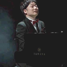 赤い蝶ネクタイを締め、YAMAHAのグランドピアノを演奏するピアニスト