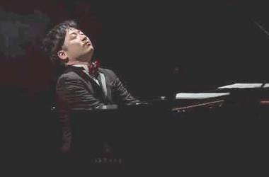 赤い蝶ネクタイを締め、感情を込めてYAMAHAのグランドピアノを演奏するピアニスト